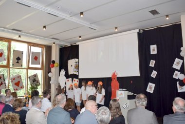 Schülerinnen und Schüler der Realschule plus Annweiler am Trifels führen eine moderne Rap-Version des Gedichts ‚Erlkönig‘ bei der Verabschiedung von Ingrid Baumgartner-Schmitt auf. Die Gruppe steht vor einem farbenfrohen Bühnenbild.