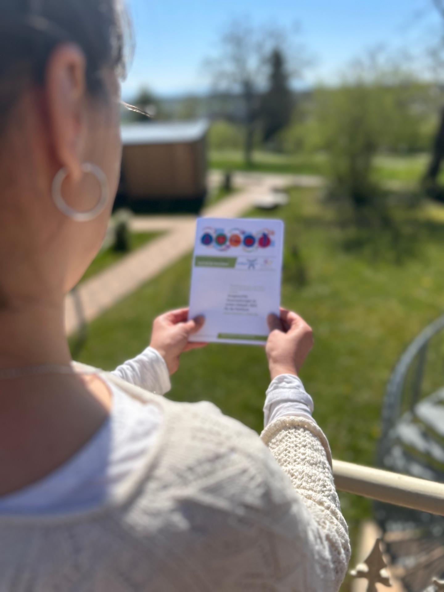 Eine Frau betrachtet im Freien die Resilienz-Broschüre der Kreisverwaltung Südliche Weinstraße, in der Veranstaltungen der Volkshochschulen vorgestellt werden.