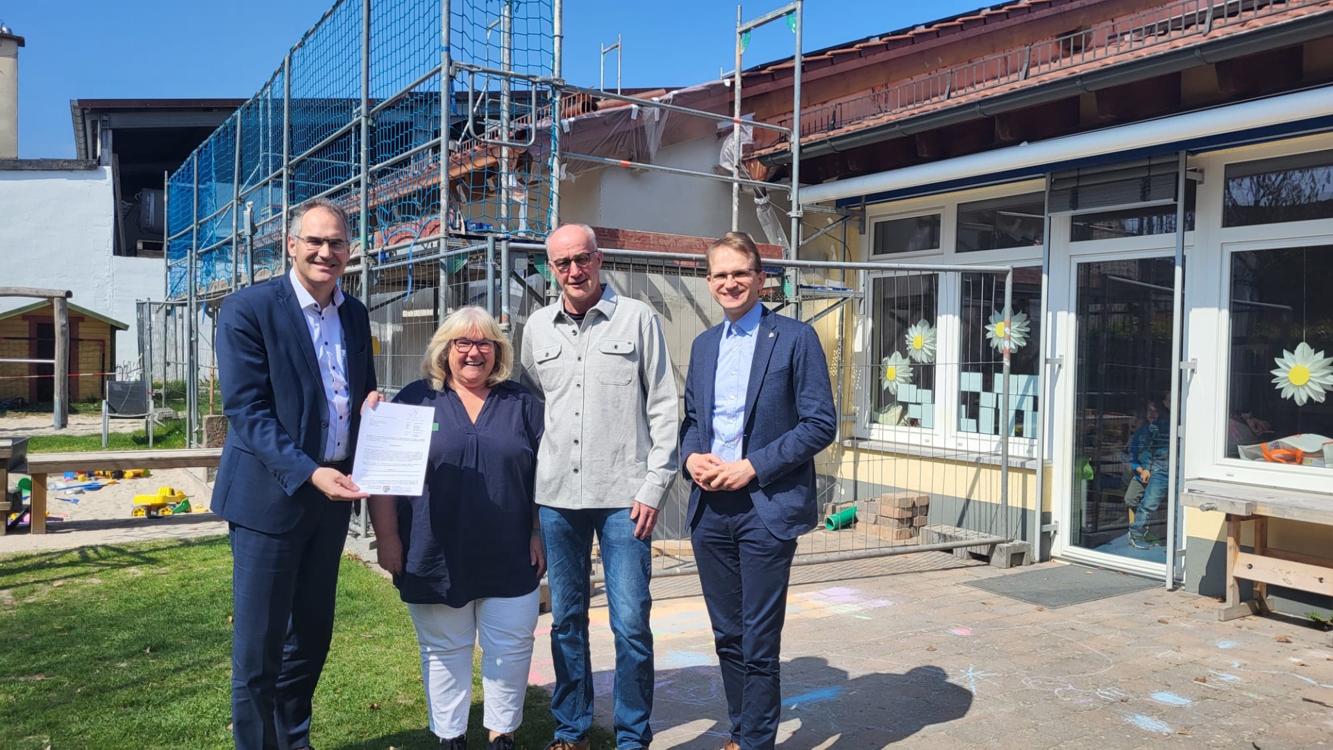 Vier Personen vor einem Kita-Gebäude, das umgebaut wird.