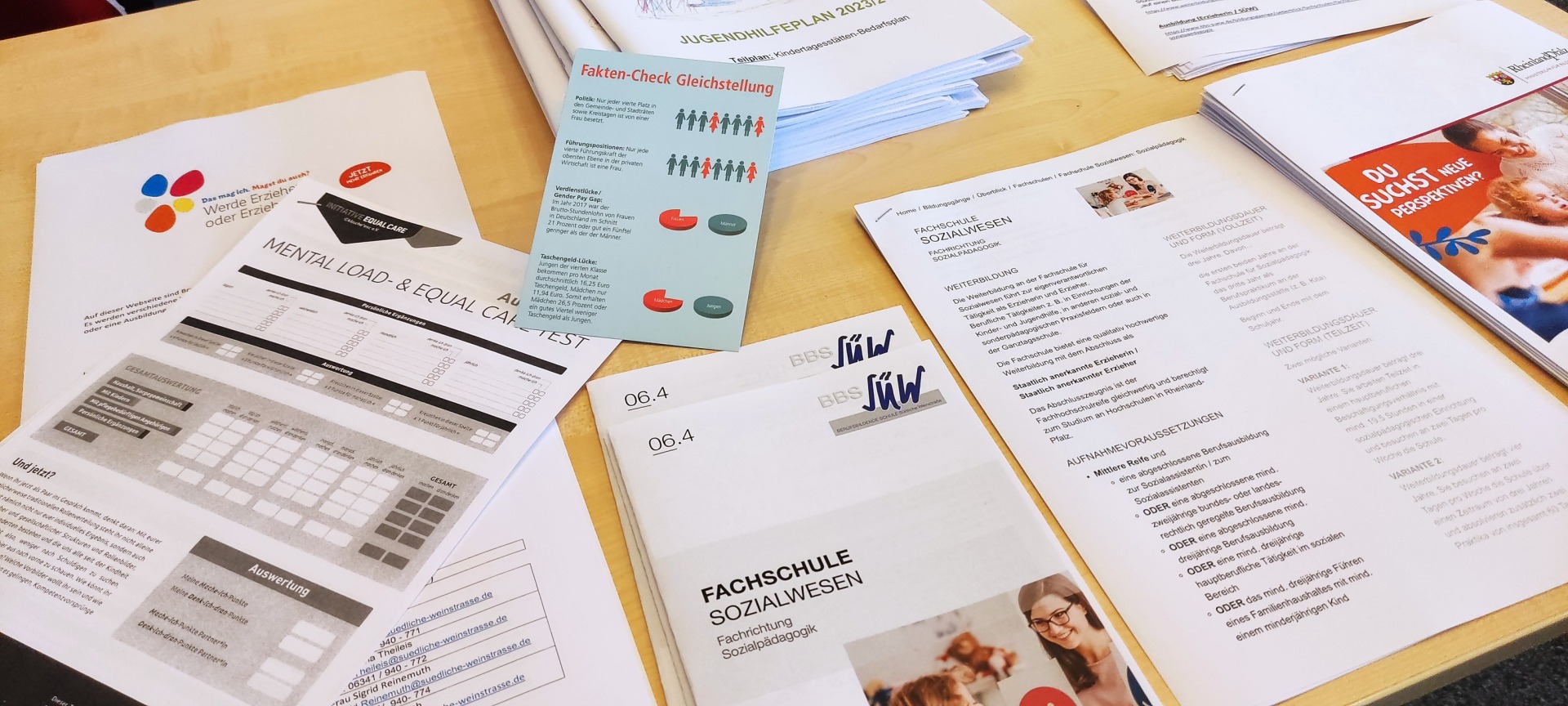 Auf einem Tisch liegen verschiedene Flyer und Informationsmaterialien, unter anderem zu den Themen "Fachschule Sozialwissen" und "Faktencheck Gleichstellung"