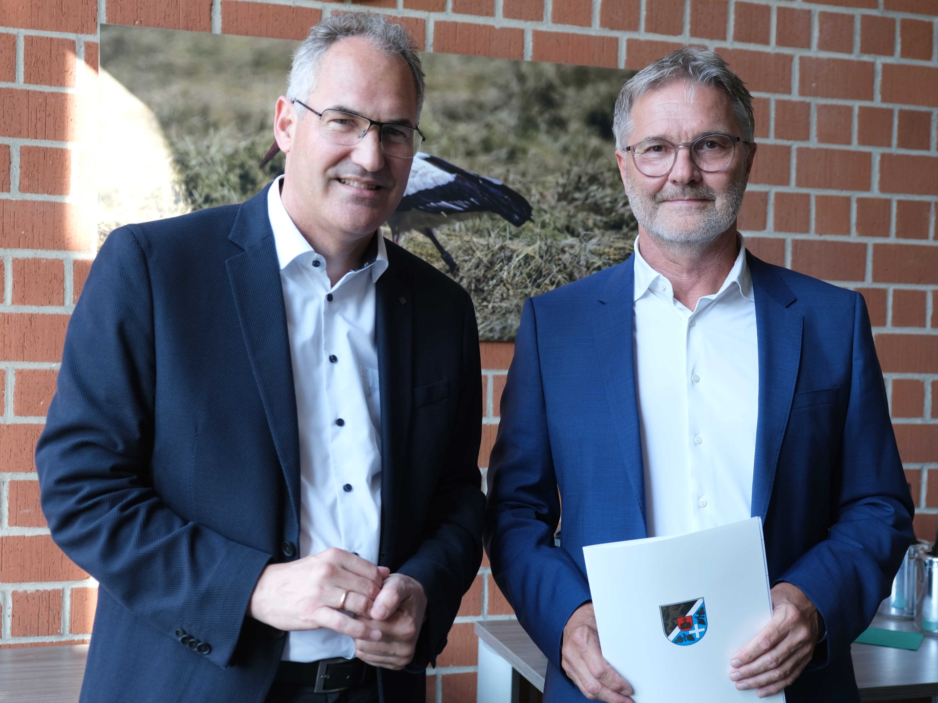 Zwei Männer, einer mit Urkunde mit SÜW-Wappen in der Hand.