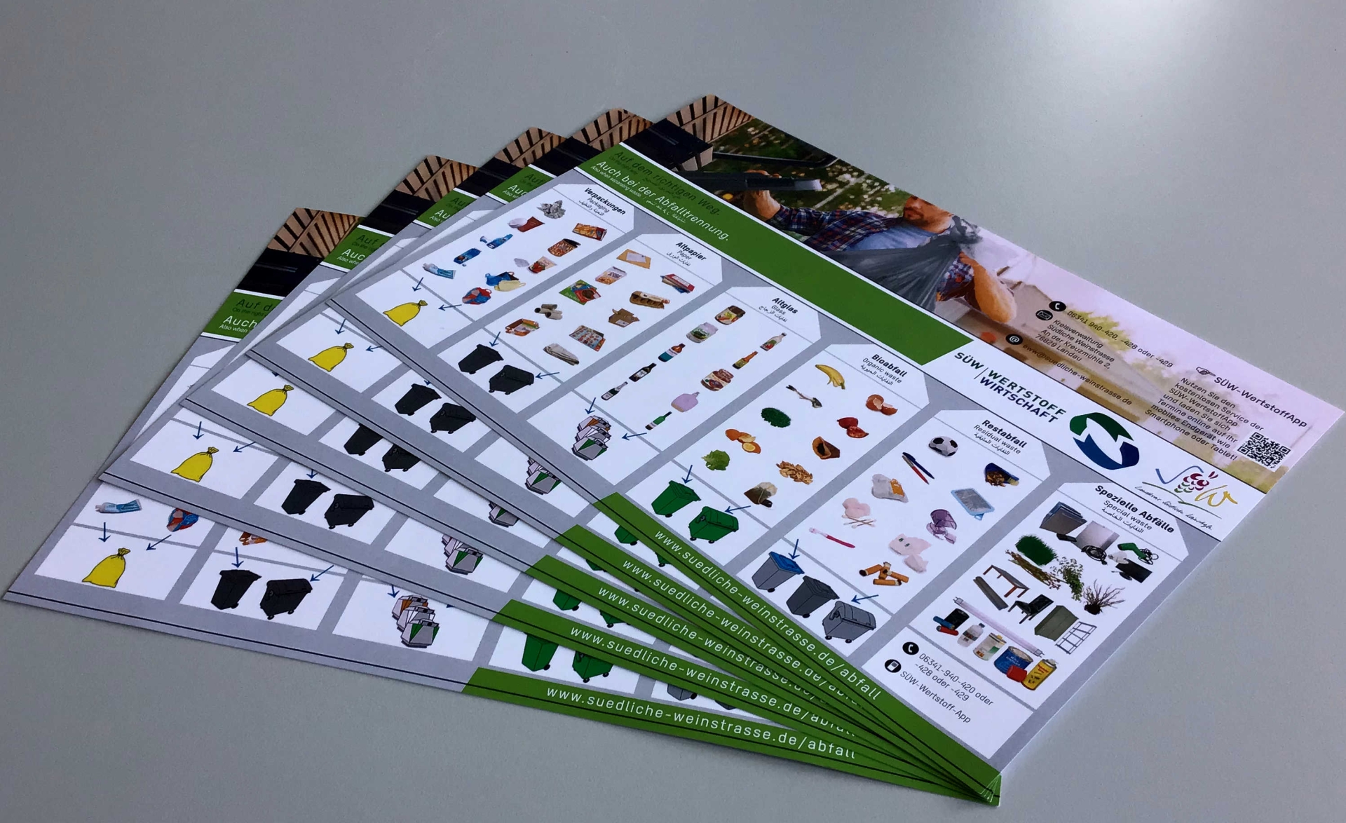 Fünf farbige Ausdrucke der neuen Abfalltrennhilfe für den Landkreis Südliche Weinstraße liegen aufgefächert auf einem Tisch.