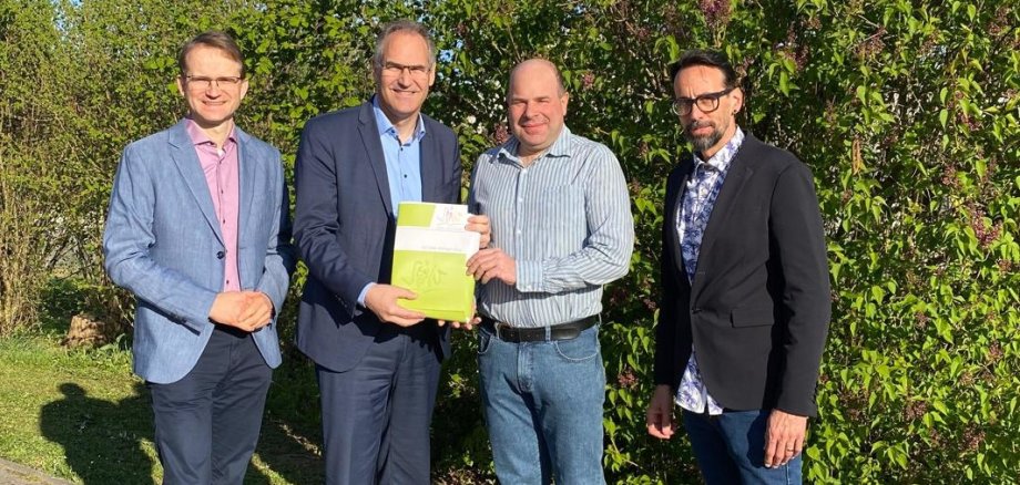 Gruppenfoto: Daniel Salm, Bürgermeister der Verbandsgemeinde Edenkoben, Landrat Dietmar Seefeldt, Dr. Martin Oberhofer, Beigeordneter von Edesheim und Christian Kocher, Ortsbürgermeister von Edesheim stehen nebeneinander und schauen in die Kamera. Im Hintergrund grüne Heckenpflanzen.