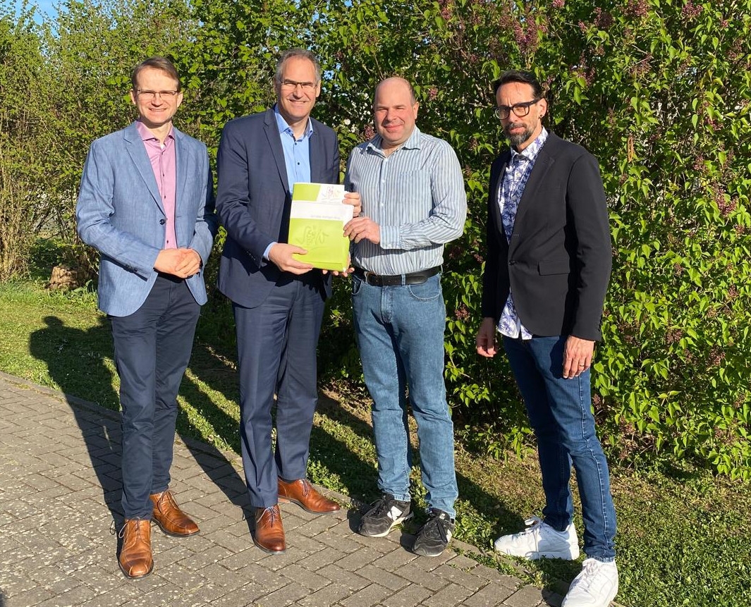 Gruppenfoto: Daniel Salm, Bürgermeister der Verbandsgemeinde Edenkoben, Landrat Dietmar Seefeldt, Dr. Martin Oberhofer, Beigeordneter von Edesheim und Christian Kocher, Ortsbürgermeister von Edesheim stehen nebeneinander und schauen in die Kamera. Im Hintergrund grüne Heckenpflanzen.