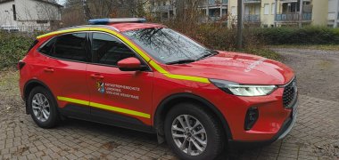 Ein roter Dienstwagen mit dem Logo des SÜW-Brand- und Katastrophenschutzes steht auf einem Parkplatz