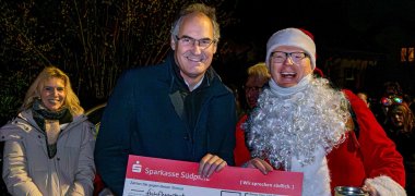 Landrat Seefeldt übergibt Patrick Kuntz, der im Weihnachtsmann-Kostüm steckt, einen Spendenscheck.