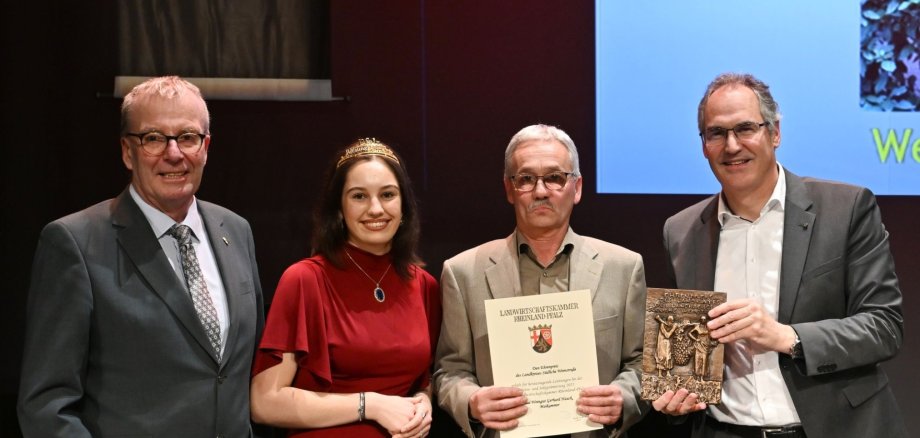 Der Ehrenpreis des Landkreises Südliche Weinstraße ging an das Weingut Gerhard Hauck aus Maikammer. Von links: Kammerpräsident Michael Horper, Pfälzische Weinkönigin Anna Antonia Cölsch, Gerhard Hauck und Landrat Dietmar Seefeldt. Foto: LWK RLP Drei Männer und eine Frau stehen um ein Holzfass. Die Frau trägt ein goldenes Diadem, ein Mann hält eine Urkunde, ein anderer eine bronzene Plakette.