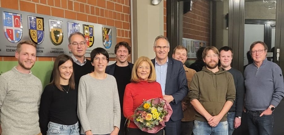 Theresia Riedmaier (Mitte) wurde als Vorsitzende des KJO-Fördervereins verabschiedet. Erster Kreisbeigeordneter Georg Kern (3. von links) folgt ihr in dieser Funktion nach. Foto: KV SÜW Eine Gruppe von Menschen steht im Sitzungsaal der Kreisverwaltung Südliche Weinstraße.