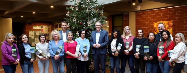Fünfzehn Personen stehen vor einem Weihnachtsbaum im Foyer der Kreisverwaltung.