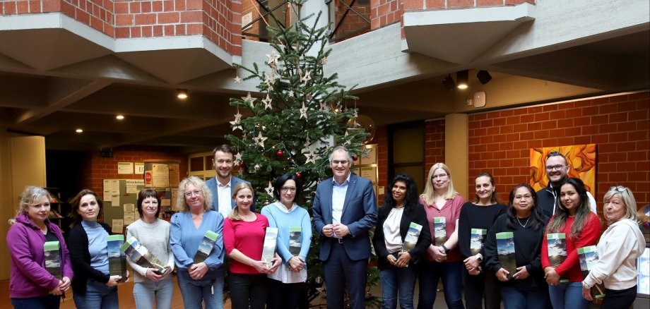15 Personen stehen im Foyer der Kreisverwaltung vor einem Weihnachtsbaum.