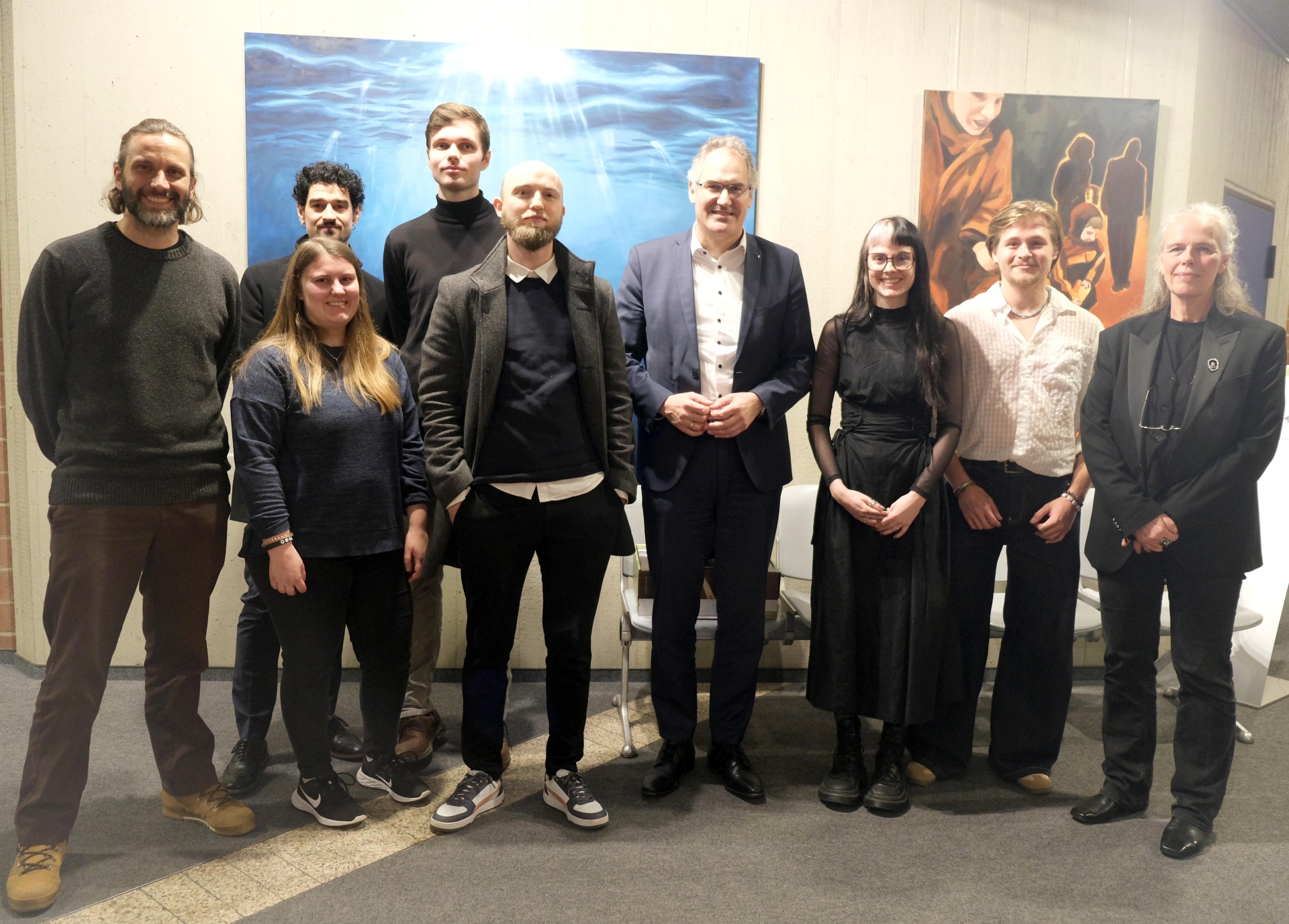 Personen stehen vor zwei großflächigen Gemälden.