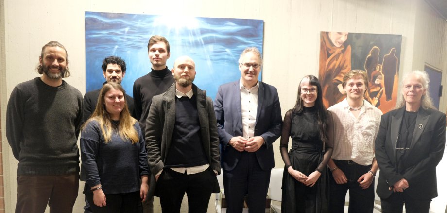 Personen stehen vor zwei großflächigen Gemälden.