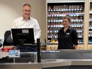 Landrat Dietmar Seefeldt steht gemeinsam mit Marktleiterin Sabrina Estelmann hinter einer Supermarktkasse im Edeka Kissel Markt in Edesheim. Foto: KV SÜW