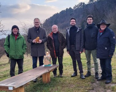 Landrat Dietmar Seefeldt (2. von links) mit Mitgliedern der Pollichia-Gruppe Edenkoben an der neuen Sitzbank auf der Theresienwiese in Edenkoben. Foto: KV SÜW Personen auf einer grünen Wiese, im Vordergrund eine Sitzbank.