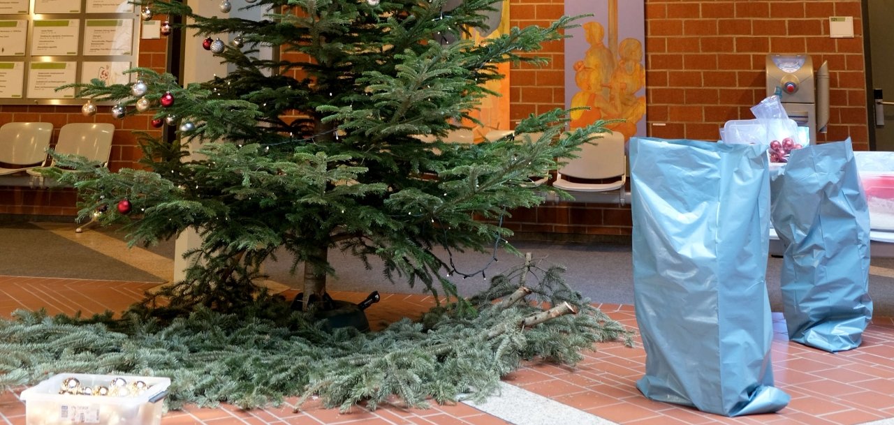 Der Tannenbaum im Foyer des Kreishauses ist halb abgeschmückt. Davor stehen ein Behälter und blaue Plastiksäcke, in denen der Baumschmuck gesammelt wird.