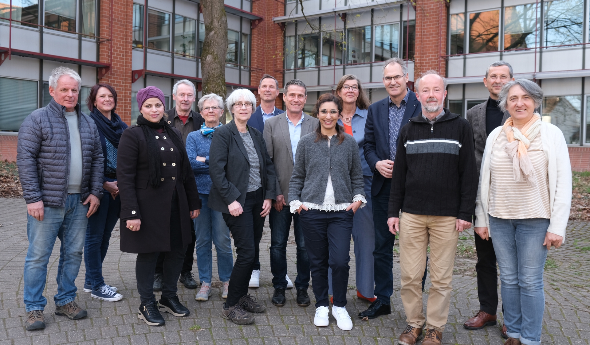 Neun der zwölf Mitglieder des neuen Beirats für Migration und Integration für den Landkreis Südliche Weinstraße sowie fünf Vertretungen des Landkreises stehen in zwei Reihen vor dem Kreishaus in Landau und lächeln in die Kamera. Foto: KV SÜW