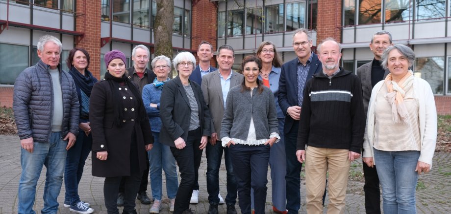 Neun der zwölf Mitglieder des neuen Beirats für Migration und Integration für den Landkreis Südliche Weinstraße sowie fünf Vertretungen des Landkreises stehen in zwei Reihen vor dem Kreishaus in Landau und lächeln in die Kamera. Foto: KV SÜW