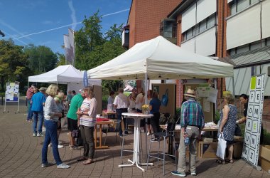 Auf dem Marktplatz der Begegnung 2023 informieren sich Besucherinnen und Besucher auf dem Platz vor dem Kreishaus in Landau an verschiedenen "Marktständen" unter Pavillons.