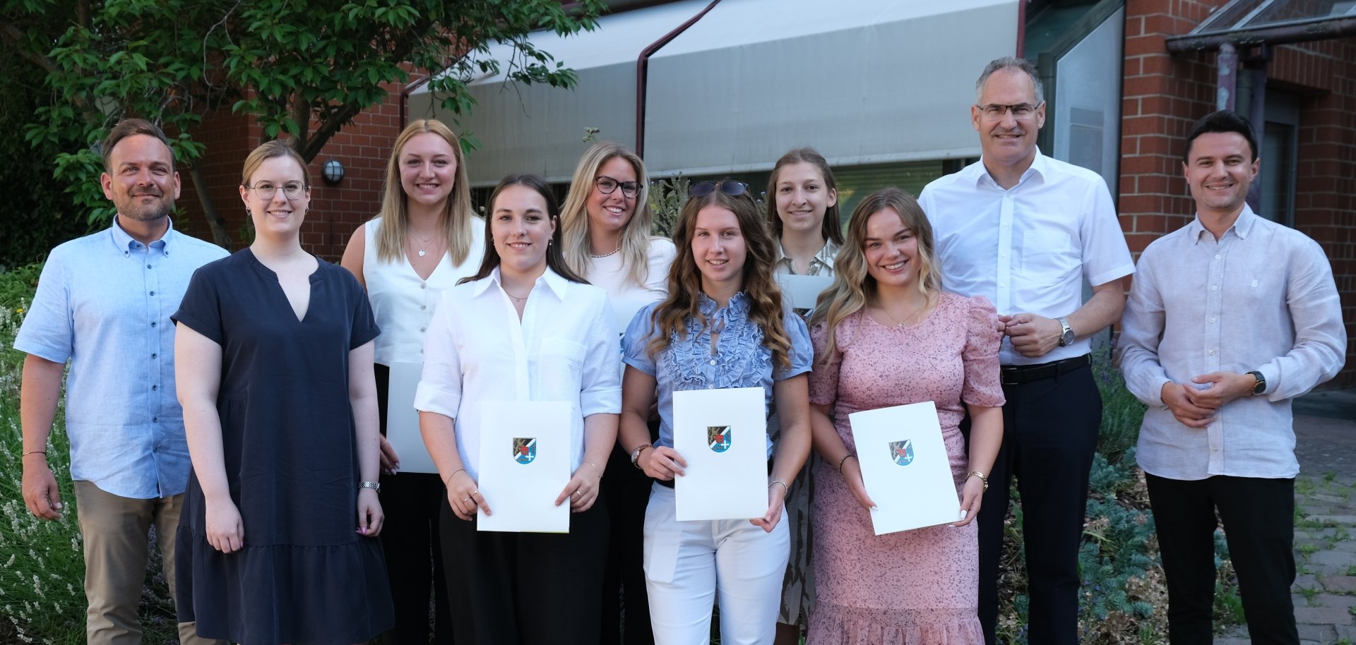 Gruppenbild: Marco Roth, Sachgebietsleiterin Personal Larissa Conrath, die Anwärterinnen Chantal Cavallo, Maxima Ott, Samira Bucke, Marlene Winter, Sarah Hauck, Selina Boschmann, Landrat Dietmar Seefeldt und der stellvertretende Personalratsvorsitzende Daniel Heilig vor dem Kreishaus in Landau.