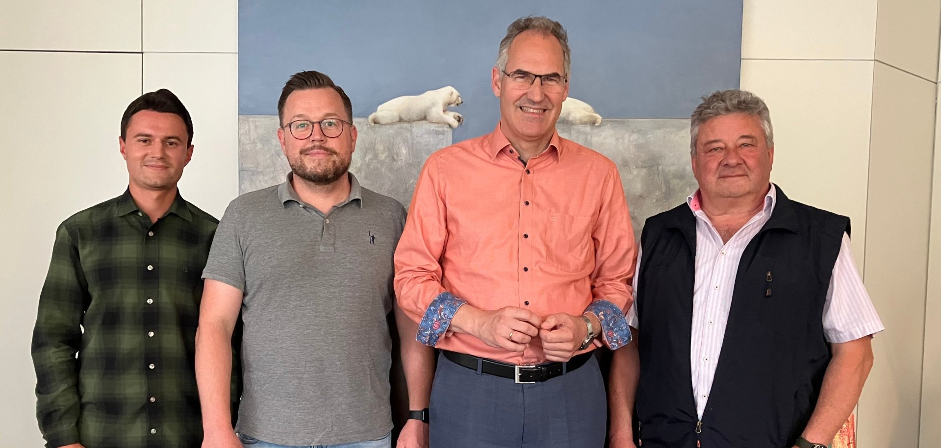 Gruppenfoto: Daniel Heilig, zweiter stellvertretender Personalratsvorsitzender, Kevin Konz, erster stellvertretender Personalratsvorsitzender, Landrat Dietmar Seefeldt und Personalratsvorsitzender Udo Baumgartner stehen nebeneinander in einem Büroraum mit weißen Wänden. Im Hintergrund ist ein Bild mit zwei Eisbären zu sehen.