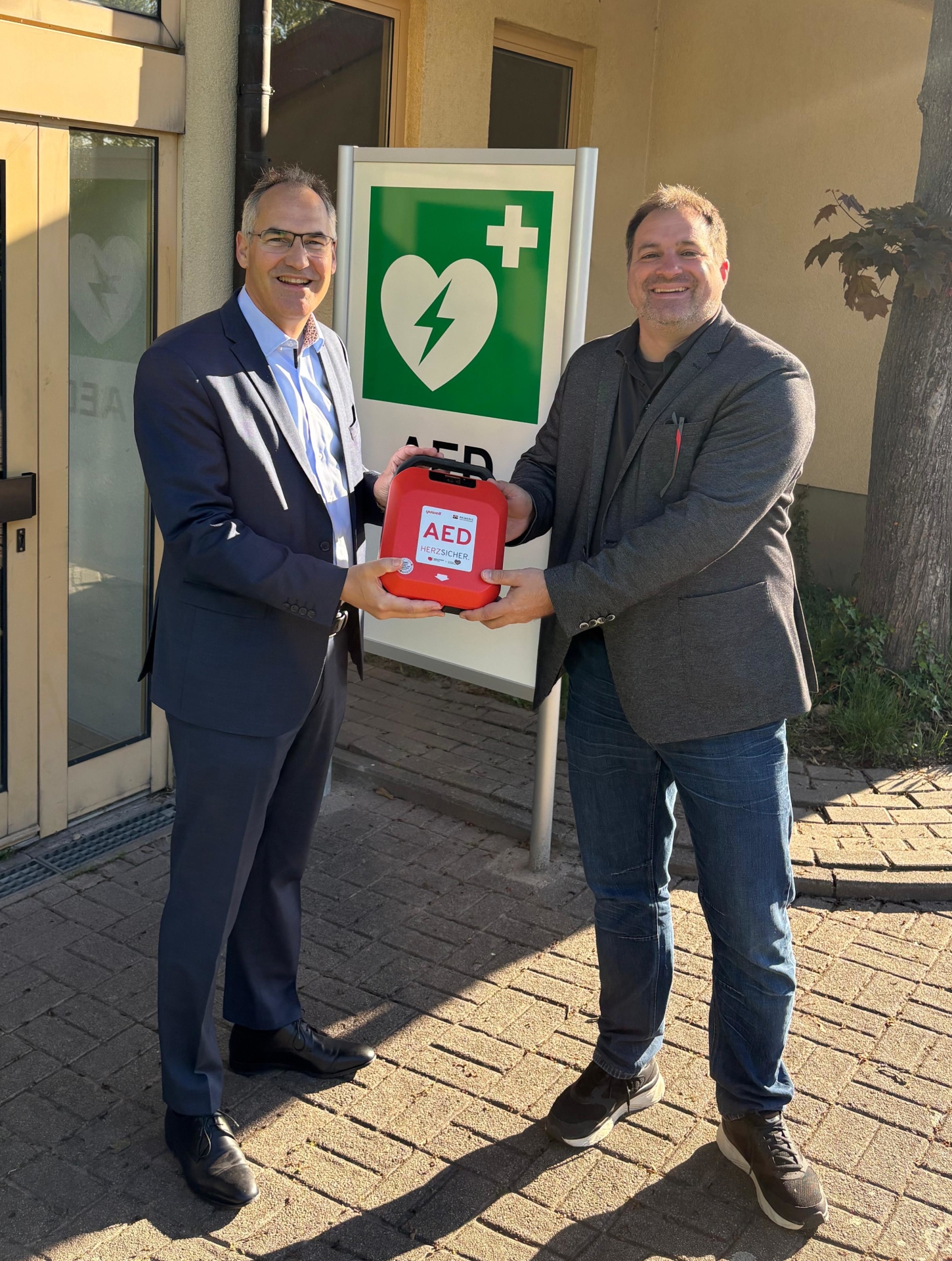 Landrat Dietmar Seefeldt und Ortsbürgermeister Martin Hammer vor der Essinger Dalberghalle.