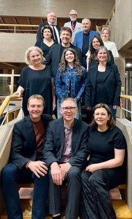 Gruppenbild: 13 Personen, darunter Marc Bender, Prof. Dr. Matthias Bahr, Martina Cukrov Jarrett und Adrian Rinck, sitzen und stehen auf einem Treppenaufgang.