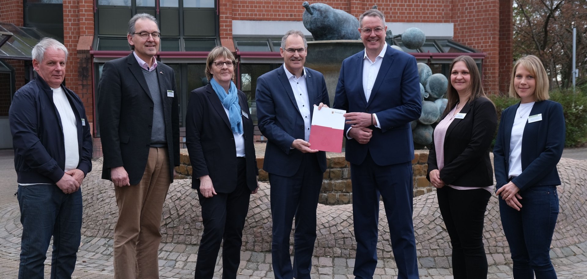 Gruppenbild vor dem Kreishaus bei der Bescheidübergabe. Von links nach rechts: Kreisbeigeordneter Werner Schreiner, Erster Kreisbeigeordneter Georg Kern, Ute Wingerter (Fachkraft Gemeindeschwester plus), Landrat Dietmar Seefeldt, Ministerpräsident Alexander Schweitzer, Nadja Hieb und Katharina Rösch (beide Fachkräfte Gemeindeschwester plus).