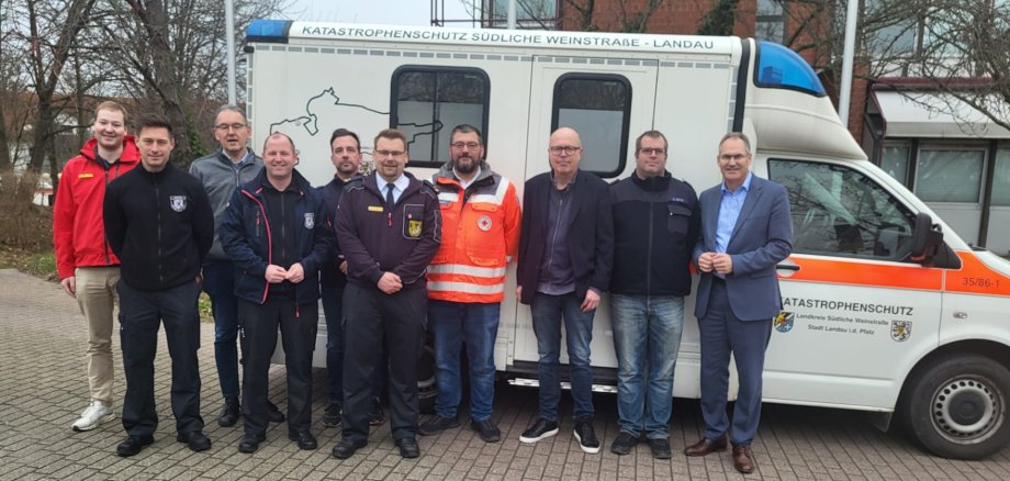 Eine Gruppe Menschen steht vor einem Krankenwagen.