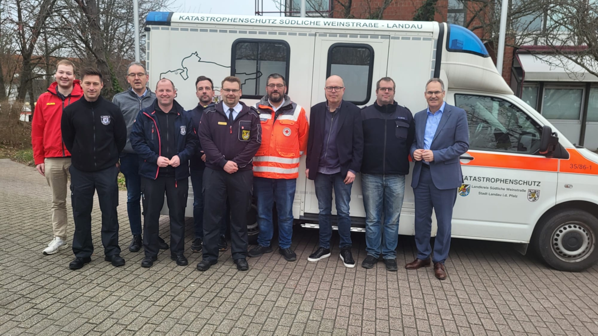 Eine Gruppe Menschen steht vor einem Krankenwagen.