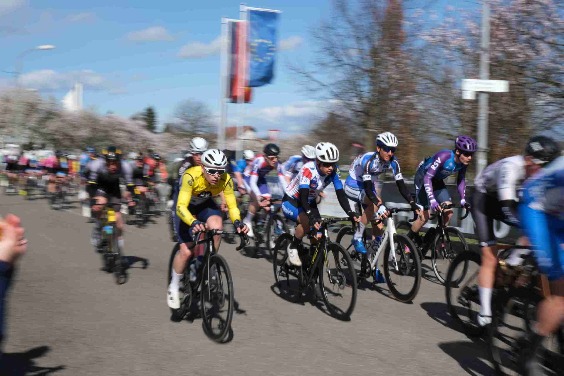 Rennradfahrer in Bewegung, im Hintergrund die Europaflagge und die Deutschlandflagge.