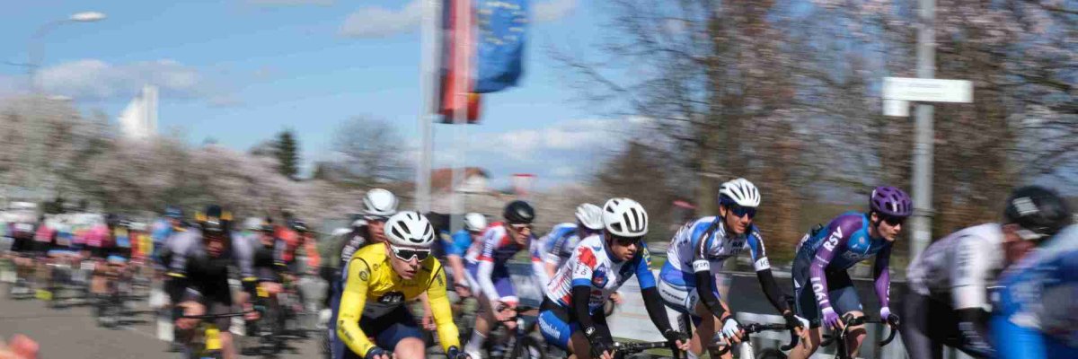 Rennradfahrer in Bewegung, im Hintergrund die Europaflagge und die Deutschlandflagge.