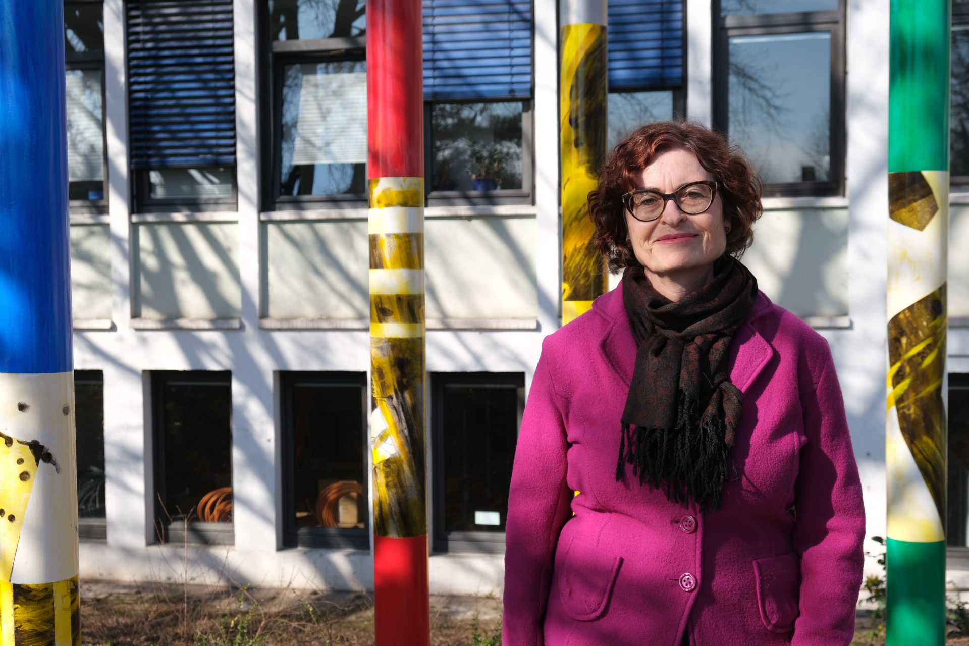 Frau vor Gebäude und bunten Stelen.