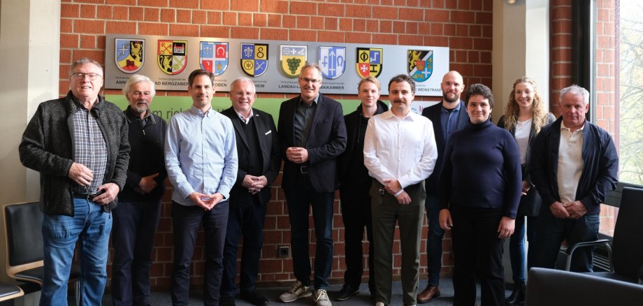 Gruppenfoto: Die Beteiligten der Beiratssitzung stehen vor einer Ziegelwand im Kreishaus Südliche Weinstraße.