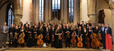 Gruppenbild: Ein Jugendorchester steht für ein Bild in einer Kirche.