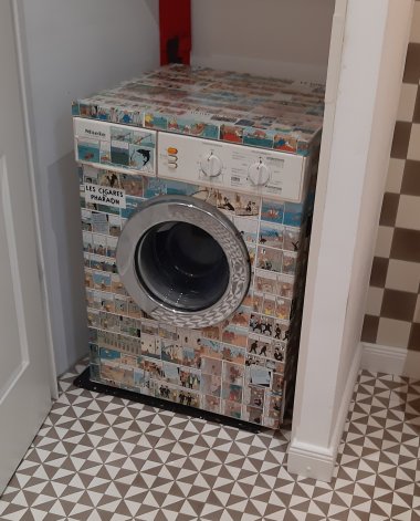 Eine Waschmaschine voll mit Stickern von „Tim und Struppi“ steht in einer Nische in einem Badezimmer.