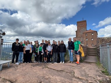 Gruppenbild: Eine Gruppe Jugendlicher mit zwei Begleitpersonen steht vor der Burg Trifels in Annweiler.