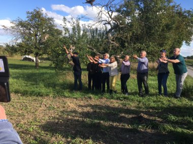 Die Jungvögel flatterten in die Freiheit. Foto: WWP Neun Personen stehen in einer Reihe auf einer Streuobstwiese und lassen junge Steinkäuze in die Freiheit fliegen.