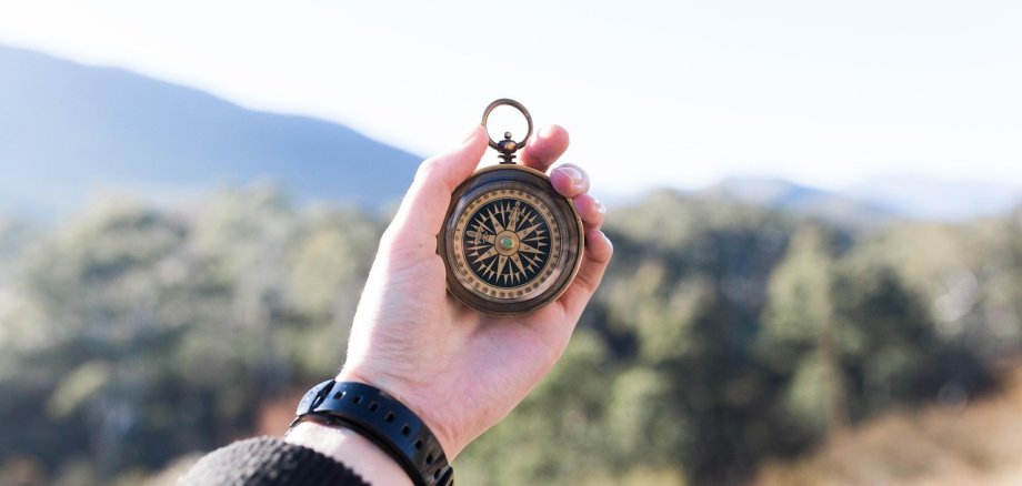 Tag der Berufsorientierung für Schülerinnen und Schüler. Symbolbild: Pixabay Ein Kompass wird in einer Hand gehalten. Im Hintergrund ist verschwommen eine bewaldete Hügel- oder Berglandschaft zu sehen.