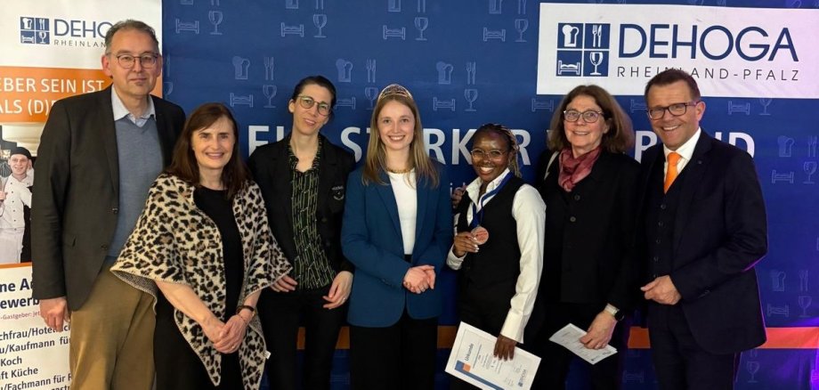 Sieben Personen stehen vor einer DEHOGA-Rheinland-Pfalz-Fotowand und lächeln in die Kamera.