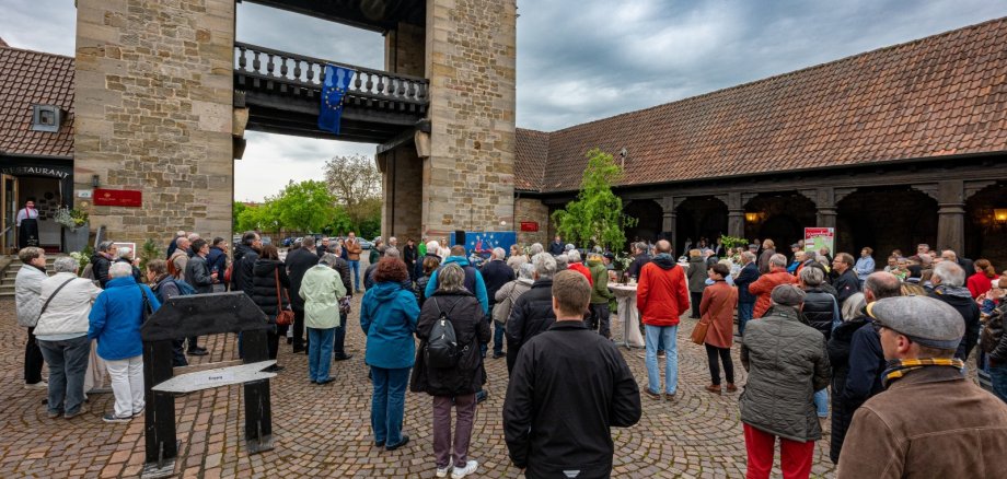 Zahlreiche Besucherinnen und Besucher stehen auf dem Pflaster am Deutschen Weintor und lauschen einem Konzert. Eine EU-Flagge hängt am Gebäude.