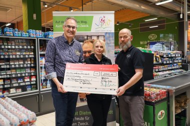 Landrat Dietmar Seefeldt (links) hält mit WASGAU-Mitarbeiterin Kristina Miller und Marktleiter Heiko Tienelt einen großen Spendenscheck in die Höhe.