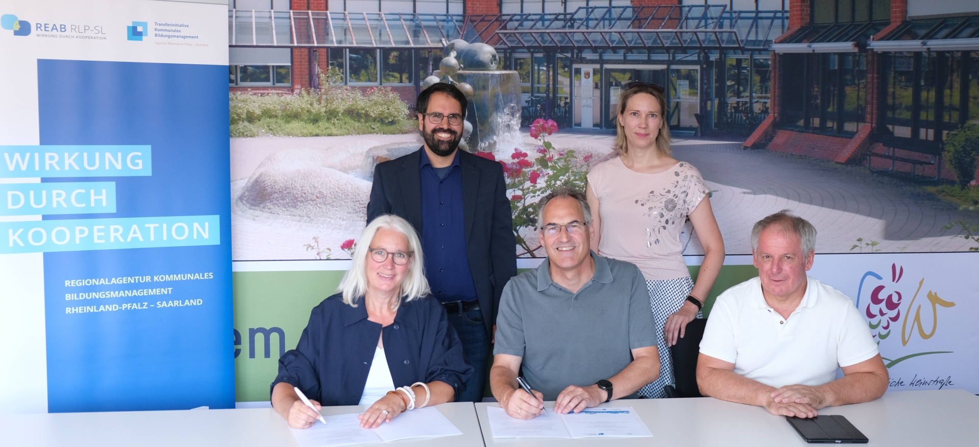 3 Personen sitzen, 2 Personen stehen vor Bannern der Regionalagentur und des Landkreises.