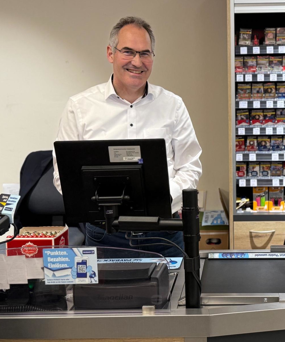 Landrat Dietmar Seefeldt steht hinter einer Supermarktkasse.
