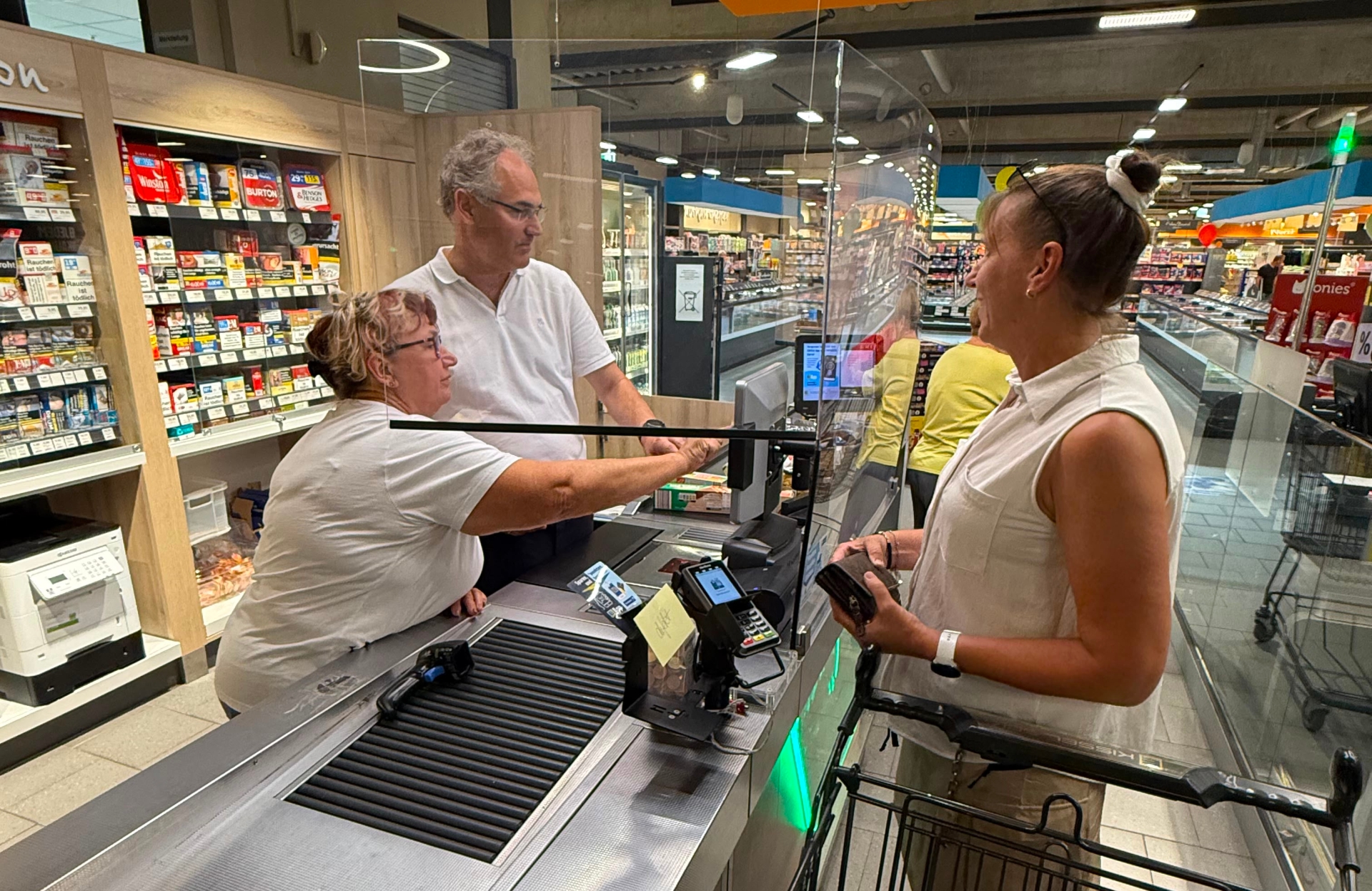 Landrat Dietmar Seefeldt hinter der Supermarktkasse im EDEKA-Kissel-SBK-Markt in Bad Bergzabern.