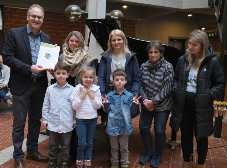 Fünf Erwachsene, drei Kinder, Urkundenübergabe.