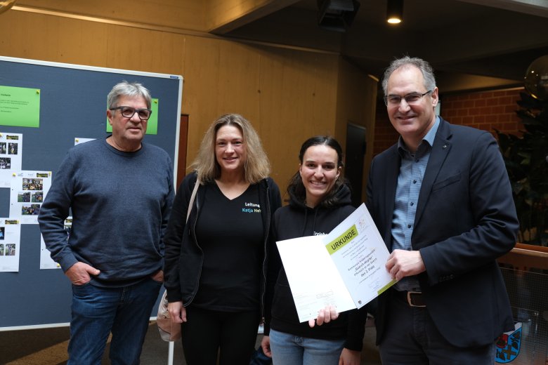 Vier Erwachsene, Urkundenübergabe.