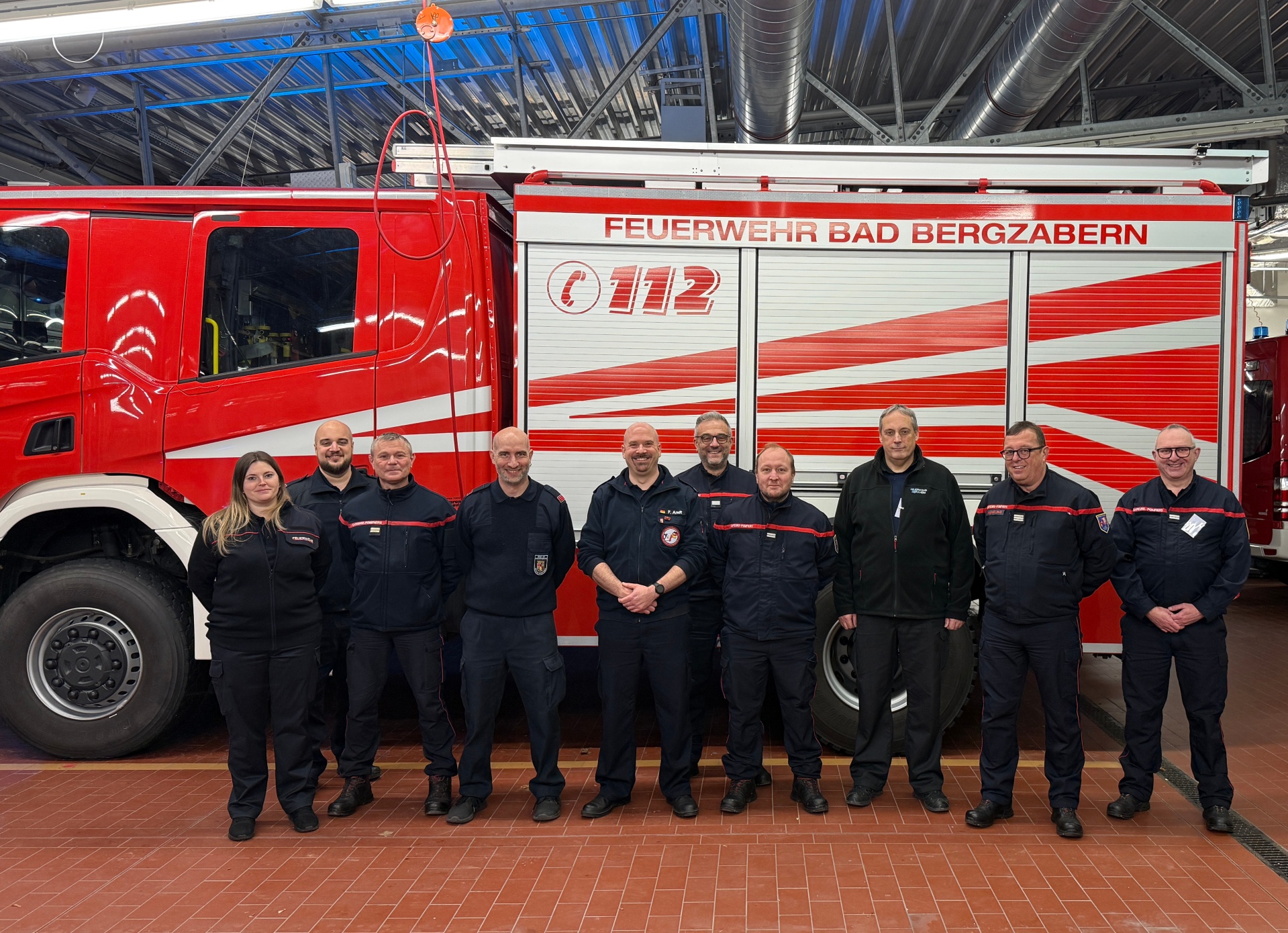 Gruppenbild der deutsch-französischen Verbindungsbeamten vor einem Feuerwehrfahrzeug.