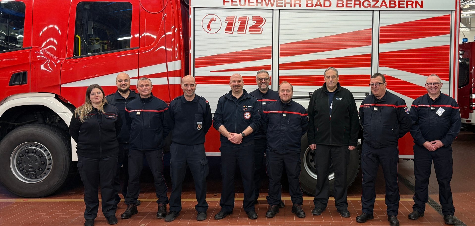 Gruppenbild der deutsch-französischen Verbindungsbeamten vor einem Feuerwehrfahrzeug.