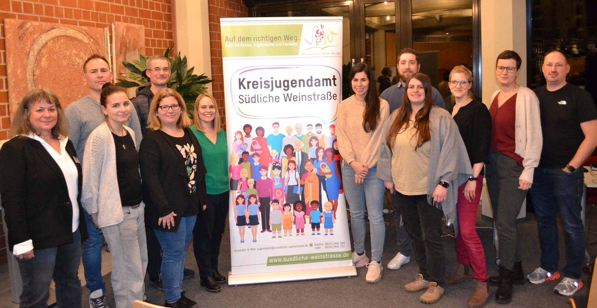 Gruppenbild: 12 Personen stehen links und rechts von einem Rollup des Kreisjugendamts Südliche Weinstraße.