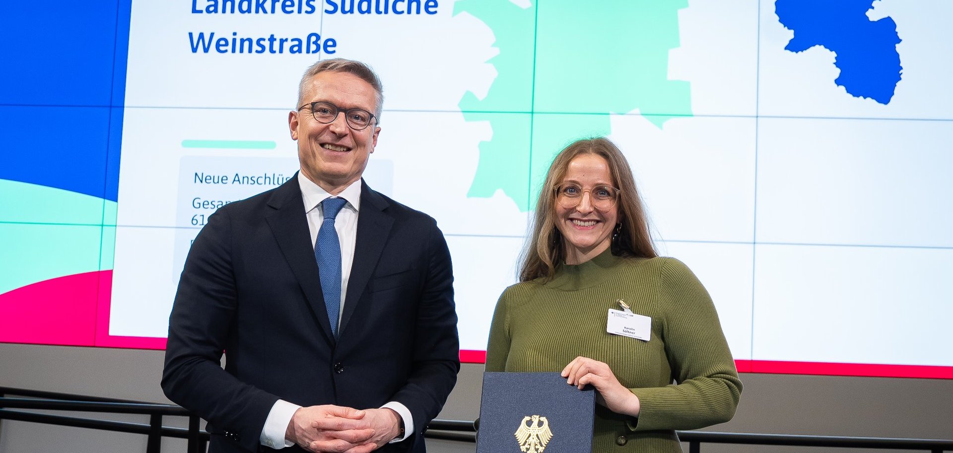 Symbolische Übergabe des Förderbescheids zur Gigabitförderung: Vertreter des Bundes überreicht die Förderung an Vertreterin des Landkreises Südliche Weinstraße.